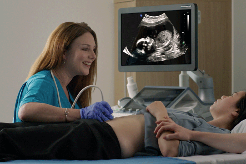 Female doctor using ultrasound machine while examining pregnant woman in hospital